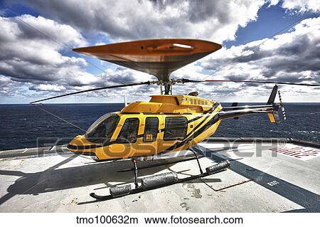 A Bell 407 utility helicopter on the helipad of an oil rig. View Large Photo Image Picture - A Bell 407 utility helicopter on the helipad of an oil rig.. Fotosearch