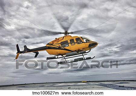 A Bell 407 utility helicopter prepares to land on an oil rig. View Large Photo Image Picture - A Bell 407 utility helicopter prepares to land on an oil rig.. Fotosearch