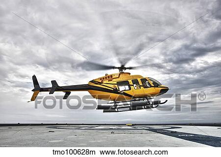 A Bell 407 utility helicopter prepares to land on an oil rig. View Large Photo Image Picture - A Bell 407 utility helicopter prepares to land on an oil rig.. Fotosearch