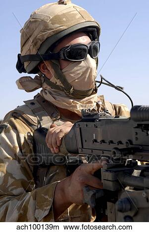 Picture - A British Army soldier mans a machine gun mounted on top of a land rover.. Fotosearch