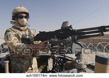 Picture - A British Army soldier mans a machine gun mounted on top of a land rover.. Fotosearch