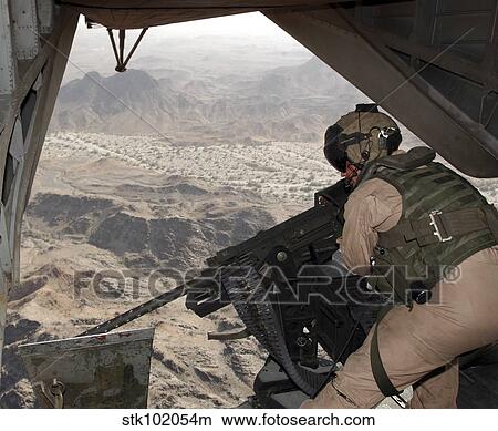 Picture - A crew chief aims the GAU-21. 50 caliber machine gun out the tail of a CH-53E Super Stallion.. Fotosearch