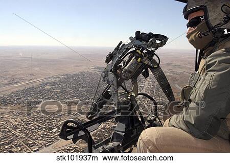 A crew chief looks for suspicious activity while manning a machine gun aboard a helicopter. View Large Photo Image Picture - A crew chief looks for suspicious activity while manning a machine gun aboard a helicopter.. Fotosearch