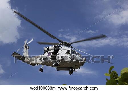 A Crew Chief looks out the side door of a helicopter in flight. View Large Photo Image Picture - A Crew Chief looks out the side door of a helicopter in flight.. Fotosearch