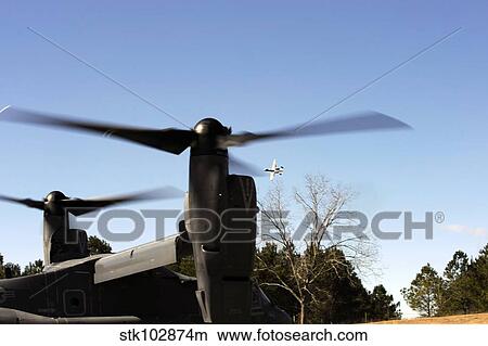 A CV-22 Osprey prepares to take off as an A-10 Thunderbolt II flies overhead. View Large Photo Image Picture - A CV-22 Osprey prepares to take off as an A-10 Thunderbolt II flies overhead.. Fotosearch