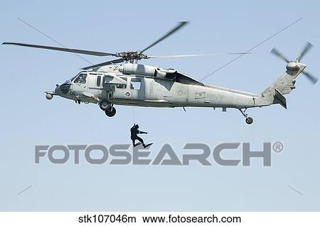 A diver is lowered from an SH-60B Seahawk helicopter. View Large Photo Image Picture - A diver is lowered from an SH-60B Seahawk helicopter.. Fotosearch