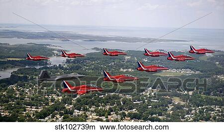 A F-22 Raptor flies in formation with the Royal Air Force Aerobatic Team, The Red Arrows. View Large Photo Image Picture - A F-22 Raptor flies in formation with the Royal Air Force Aerobatic Team, The Red Arrows.. Fotosearch