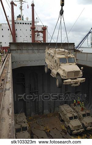 Picture - A harbor crane lifts a mine-resistant, ambush-protected vehicle from the hull of a cargo vessel.. Fotosearch