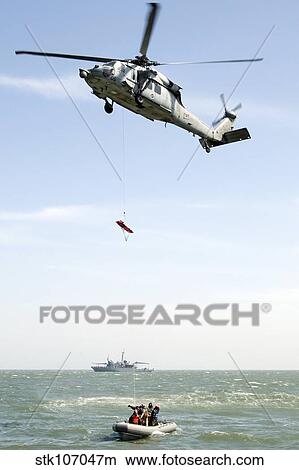 A litter is lowered from a SH-60B helicopter during a medical evacuation. View Large Photo Image Picture - A litter is lowered from a SH-60B helicopter during a medical evacuation.. Fotosearch