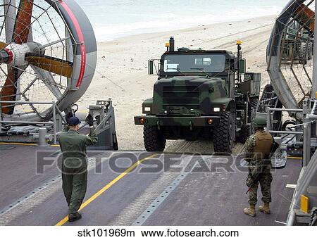 A loadmaster guides a Marine 7-ton truck onto his Landing Craft, Air Cushioned. View Large Photo Image Picture - A loadmaster guides a Marine 7-ton truck onto his Landing Craft, Air Cushioned.. Fotosearch