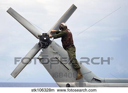 Picture - A Marine conducts maintenance on the tail of an UH-1N Huey helicopter.. Fotosearch
