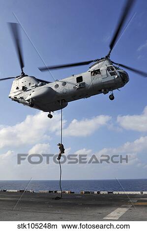 A Marine fast ropes from a CH-46E Sea Knight helicopter. View Large Photo Image Picture - A Marine fast ropes from a CH-46E Sea Knight helicopter.. Fotosearch