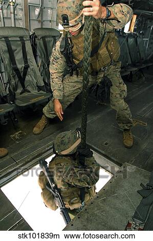 Picture - A Marine sends a fellow Marine down the hell hole of a CH-53E Super Stallion.. Fotosearch