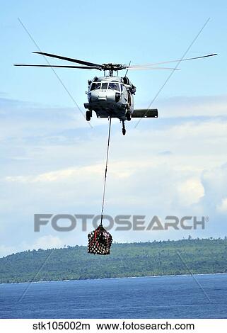 A MH-60 Knighthawk carries supplies during an underway replenishment. View Large Photo Image Picture - A MH-60 Knighthawk carries supplies during an underway replenishment.. Fotosearch