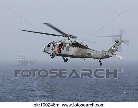 A MH-60S Knighthawk conducts a vertical replenishment at sea. View Large Photo Image Picture - A MH-60S Knighthawk conducts a vertical replenishment at sea.. Fotosearch