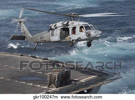 A MH-60S Knighthawk conducts a vertical replenishment at sea. View Large Photo Image Picture - A MH-60S Knighthawk conducts a vertical replenishment at sea.. Fotosearch