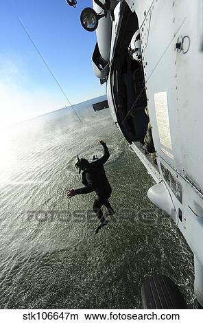 A naval air crewman jumps from an MH-60S Sea Hawk helicopter. View Large Photo Image Picture - A naval air crewman jumps from an MH-60S Sea Hawk helicopter.. Fotosearch