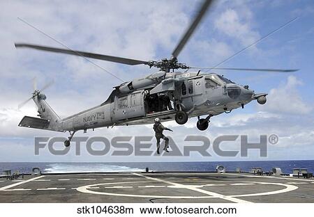 A naval aircrewman is hoisted into an MH-60S Sea Hawk helicopter. View Large Photo Image Picture - A naval aircrewman is hoisted into an MH-60S Sea Hawk helicopter.. Fotosearch