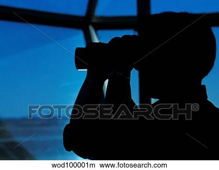 A Navy air traffic controller maintains an alert watch with binoculars in the control tower. View Large Photo Image Picture - A Navy air traffic controller maintains an alert watch with binoculars in the control tower.. Fotosearch