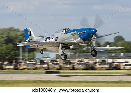 A P-51 Mustang takes off from Oshkosh, Wisconsin. View Large Photo Image Picture - A P-51 Mustang takes off from Oshkosh, Wisconsin.. Fotosearch