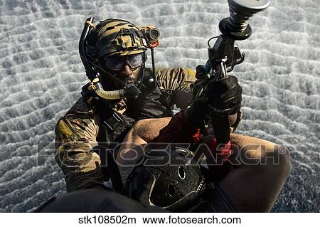 A pararescueman is hoisted into an HH-60G Pave Hawk. View Large Photo Image Picture - A pararescueman is hoisted into an HH-60G Pave Hawk.. Fotosearch