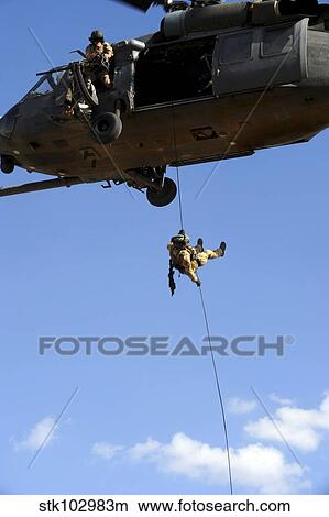 A pararescueman rappels from an HH-60 Pavehawk helicopter. View Large Photo Image Picture - A pararescueman rappels from an HH-60 Pavehawk helicopter.. Fotosearch