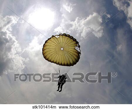A paratrooper descends through the sky during the day. View Large Photo Image Picture - A paratrooper descends through the sky during the day.. Fotosearch
