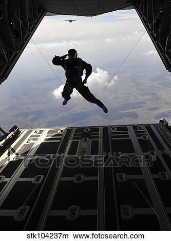 A paratrooper salutes as he jumps out of a C-130J Super Hercules. View Large Photo Image Picture - A paratrooper salutes as he jumps out of a C-130J Super Hercules.. Fotosearch