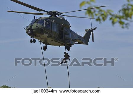 A pathfinder of the Belgian Army fast-roping from a NH90 helicopter. View Large Photo Image Picture - A pathfinder of the Belgian Army fast-roping from a NH90 helicopter.. Fotosearch