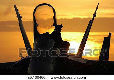 Picture - A plane captain enjoys a sunset from atop an F/A-18 Hornet.. Fotosearch