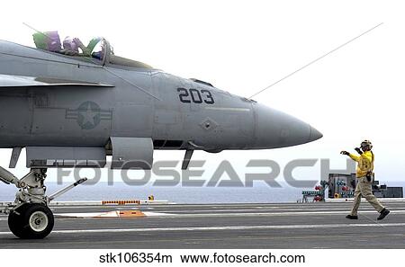 A Sailor directs an F/A-18 18E Super Hornet across the flight deck of USS Nimitz. View Large Photo Image Picture - A Sailor directs an F/A-18 18E Super Hornet across the flight deck of USS Nimitz.. Fotosearch