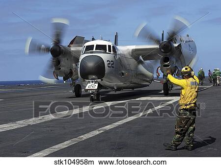 Picture - A Sailor gives hand signals to the pilot of a C-2A Greyhound.. Fotosearch