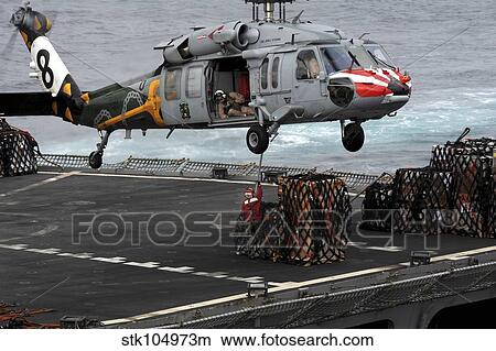 A Sailor hooks cargo to an MH-60S Sea Hawk helicopter. View Large Photo Image Picture - A Sailor hooks cargo to an MH-60S Sea Hawk helicopter.. Fotosearch