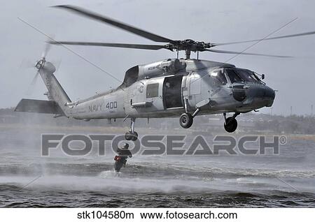 A search and rescue swimmer jumps from an SH-60F Sea Hawk helicopter. View Large Photo Image Picture - A search and rescue swimmer jumps from an SH-60F Sea Hawk helicopter.. Fotosearch