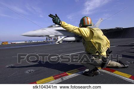 A shooter signals the launch of an F/A-18 Super Hornet. View Large Photo Image Picture - A shooter signals the launch of an F/A-18 Super Hornet.. Fotosearch