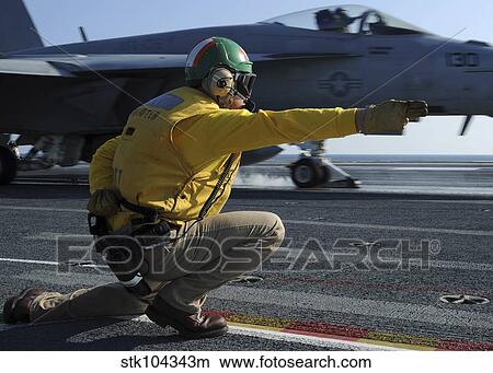 A shooter signals the launch of an F/A-18 Super Hornet. View Large Photo Image Picture - A shooter signals the launch of an F/A-18 Super Hornet.. Fotosearch