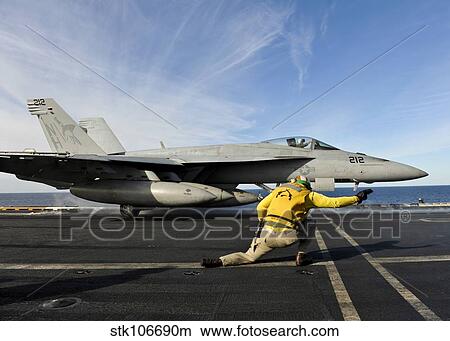 A shooter signals to launch an F/A-18E Super Hornet aboard USS Nimitz. View Large Photo Image Picture - A shooter signals to launch an F/A-18E Super Hornet aboard USS Nimitz.. Fotosearch