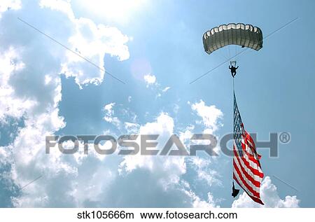 A skydiver carries a U. S. flag while descending through the sky. View Large Photo Image Picture - A skydiver carries a U. S. flag while descending through the sky.. Fotosearch