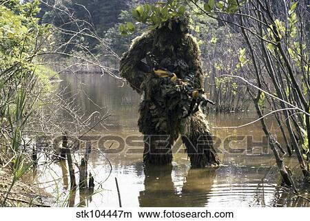 A sniper dressed in a ghillie suit crosses a stream while on patrol. View Large Photo Image Picture - A sniper dressed in a ghillie suit crosses a stream while on patrol.. Fotosearch