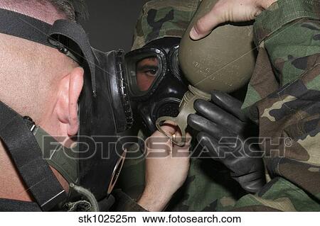 Picture - A solder assists a Marine in helping him fit his gas mask's drinking tube into his canteen.. Fotosearch