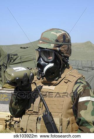 A soldier drinks water from a canteen while wearing a gas mask. View Large Photo Image Picture - A soldier drinks water from a canteen while wearing a gas mask.. Fotosearch