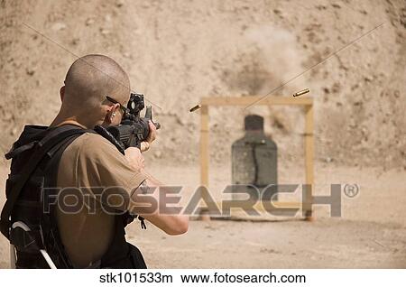 A soldier fires three round bursts from a M4 carbine assault rifle. View Large Photo Image Picture - A soldier fires three round bursts from a M4 carbine assault rifle.. Fotosearch