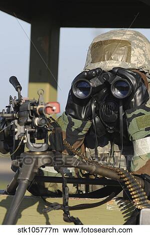 A soldier looks through binoculars from his outpost. View Large Photo Image Picture - A soldier looks through binoculars from his outpost.. Fotosearch