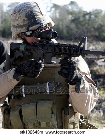 A soldier looks through the scope of a M-4 carbine. View Large Photo Image Picture - A soldier looks through the scope of a M-4 carbine.. Fotosearch