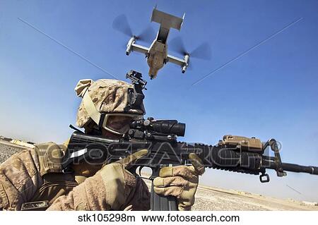 A soldier provides security as an MV-22 Osprey lands in Afghanistan. View Large Photo Image Picture - A soldier provides security as an MV-22 Osprey lands in Afghanistan.. Fotosearch