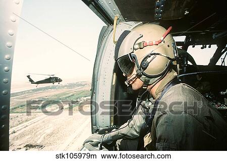 Picture - A soldier scans the horizon from inside a helicopter during Operation Desert Storm.. Fotosearch