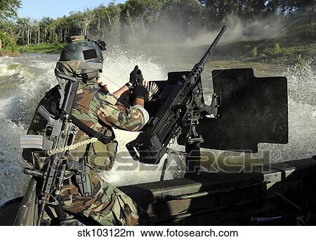 Picture - A Special Warfare Combatant-craft Crewman reloading an M2 Heavy Barrel. 50 caliber machine gun.. Fotosearch