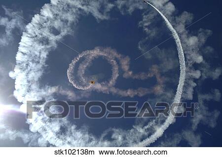 A stunt plane flies around a parachutist. View Large Photo Image Picture - A stunt plane flies around a parachutist.. Fotosearch