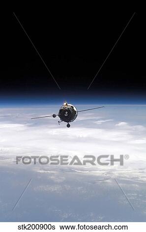 Stock Photograph - A supply vehicle backdropped by the blackness of space and Earth's horizon.. Fotosearch