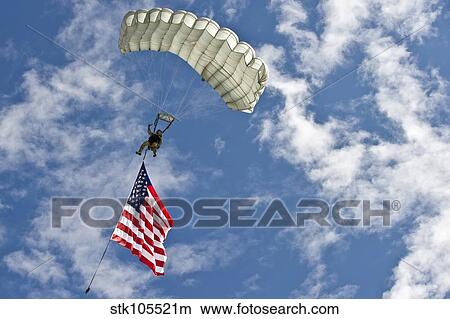 Picture - A U. S. Air Force member glides through the sky with theAmerican flag.. Fotosearch